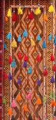 Decorative cords with tassels and traditional iranian carpet in old Grand Bazaar, located in the historical center of the Isfahan, Iran. Tasselled cords on oriental carpet background