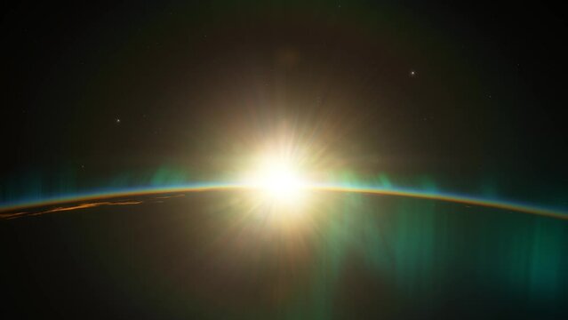 A spectacular view of the Earth from space, showing a radiant sunrise and the northern lights