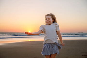 Adorable happy smiling little girl on beach vacation at sunset. Handsome cute preschool child with long blond hairs having fun on family vacations. - obrazy, fototapety, plakaty