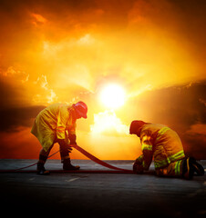 Firefighters are preparing their fire hoses to combat the blaze - obrazy, fototapety, plakaty