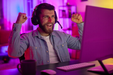 Excited gamer celebrates victory at PC in neon light