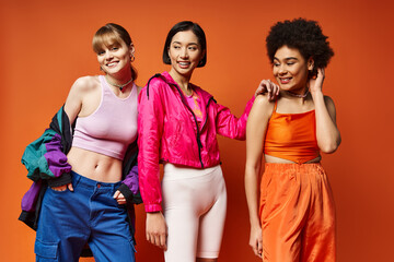 Three beautiful women of Caucasian, Asian, and African American descent stand together on a vibrant...