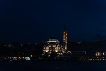 View from the ferry to the illuminated New Mosque, Yeni Kami at night, Istanbul, Turkey.