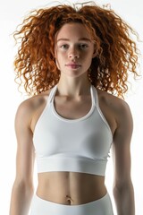 Attractive young woman with red hair in white sports bra top and leggings doing indoor workout routine