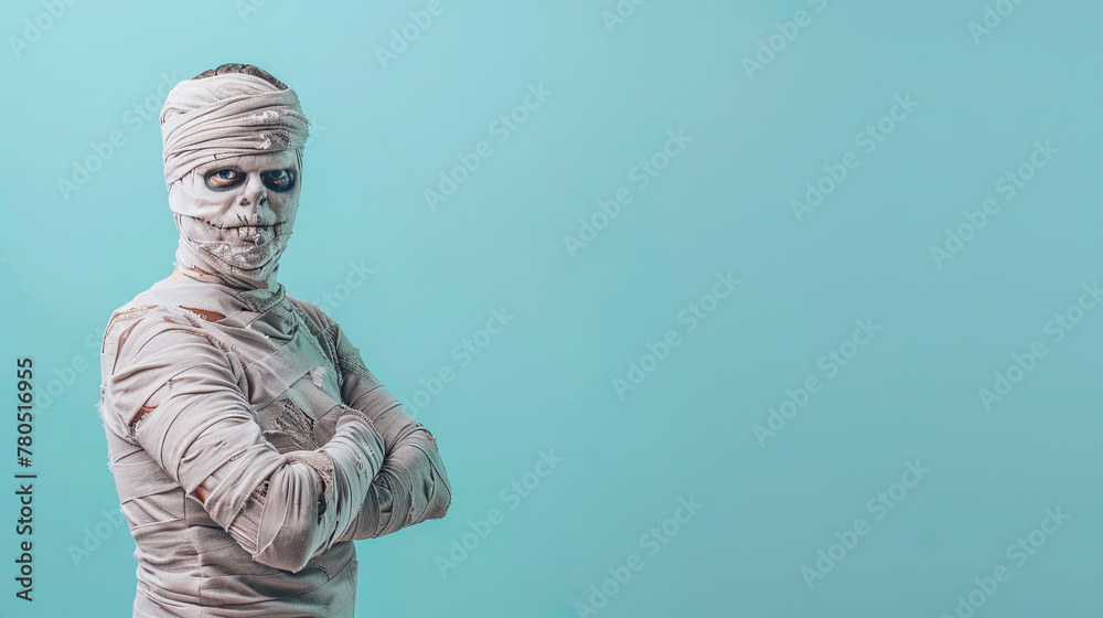 Wall mural young man in costume dressed as a halloween cosplay of a scary mummy on blue background - Wall murals
