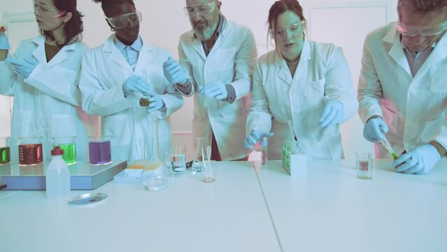 Focused scientists are conducting a chemical experiment with colorful liquids in a modern laboratory