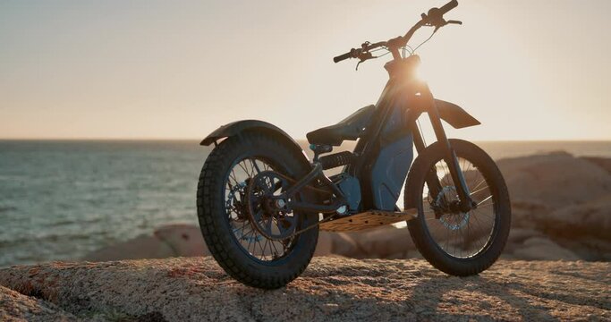 Beach, sky and electric motorbike for transport, adventure and sustainable sport in nature at summer race. Carbon neutral travel, eco friendly bike or motorcycle with calm ocean, mountain and machine