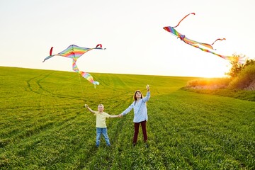 Smiling girl and brother boy standing and holding hands with flying colorful kites on the high...