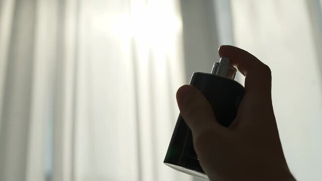 A man sprays perfume from a bottle.
Drops of perfume in the sun's rays opposite the window in slow motion bottle, sprays, spray