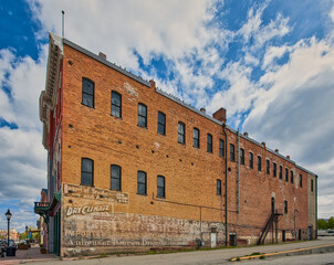 The brick facade of a historic building in a Colorado small town stands tall against the sky, encapsulating the timeless heart land spirit amidst the surrounding natural mountains