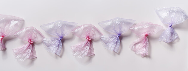 Plastic free, environmental protection concept. Empty used plastic bags in row, wide banner. Aesthetic top view pink and blue disposable transparent polyethylene packets. Plastic bag free day
