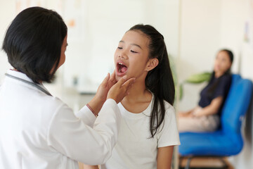 Pediatrician asking girl to open mouth when checking her throat - obrazy, fototapety, plakaty