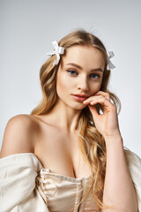 Obraz premium A young, blonde woman exudes tranquility with a white bow gracefully adorning her hair in a studio setting.