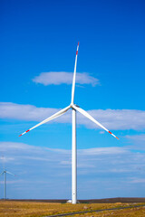 Fleet of power generators in motion. The blades of the wind farm rotate against the sky. The concept of extracting electricity from renewable sources. Wind turbine to generate electricity.