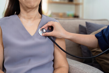 cardiologist visit elderly patient at home. cardiologist use stethoscope to listen to heart rate of...