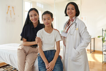 Obraz premium Smiling pediatrician standing next to teenage patient and her mother
