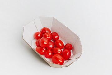 Cherry tomatoes are in a cardboard box on a white background