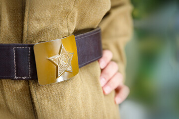 Vintage buckle with the image of a star, hammer and sickle from the Great Patriotic War, worn on a khaki military uniform.