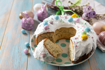 Glazed easter lemon cake decorated with confectionery and mini chocolate eggs candy on a wooden...