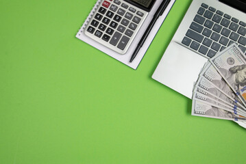 office desk with laptop calculator and other office supplies on isolated green background with copy space.