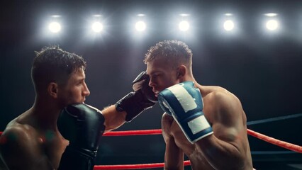 Cinematic Super Slow Motion Sports Footage with Two Professional Boxers Fighting in a Ring. Male Athlete Punching the Opponent in the Face. Sweat Spraying Everywhere From the Heavy Impact