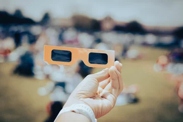 Foto op Canvas Asian hand wear smart watch holding paper solar eclipse with blurry crowd people watching totality show in Dallas, Texas, April 8, scratch resistant polymer lenses filter out harmful ultraviolet © trongnguyen