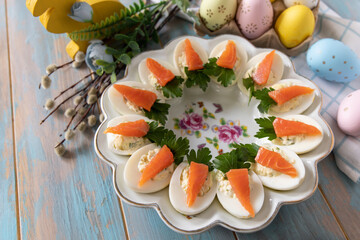 Stuffed eggs with cheese and salted salmon in the form of a carrot on a wooden table. - 780550330