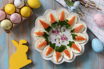 Stuffed eggs with cheese and salted salmon in the form of a carrot on a wooden table. - 780551520