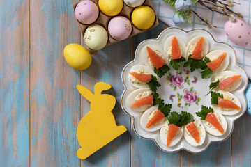 Stuffed eggs with cheese and salted salmon in the form of a carrot on a wooden table. - 780552119