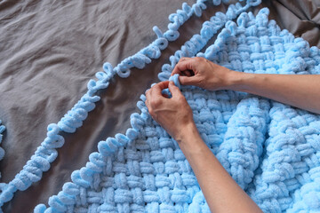 A woman makes a blue blanket for her grandson with her own hands. Free space for text.