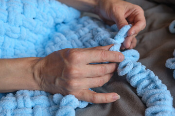 A woman makes a blue blanket for her grandson with her own hands. Free space for text.