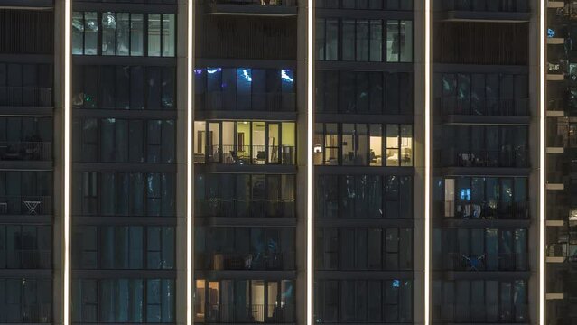 Tall blocks of flats with glowing windows located in new residential district of city aerial timelapse. Evening light in rooms in towers and skyscrapers