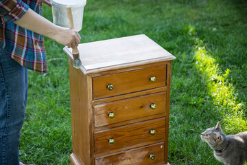 Painting a wooden furniture outdoors, an eco-friendly re-use business. - obrazy, fototapety, plakaty