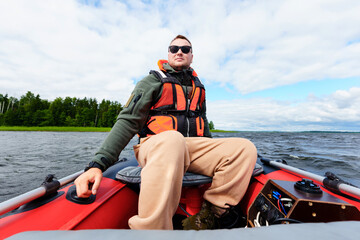 Portrait of a man driving a motorboat on a sunny day. Safety vest on a man