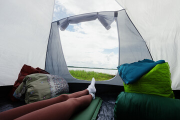 Vacation in nature. The concept of a tent camp. Women's legs in a tent , inside view