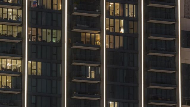 Tall blocks of flats with glowing windows located in residential district of city aerial timelapse. Evening light in rooms in top of towers and skyscrapers