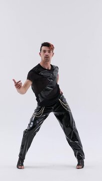 Extraordinary Caucasian man wearing high heels dancing vogue over white background. Showing dance performance and choreography. Vertical video.