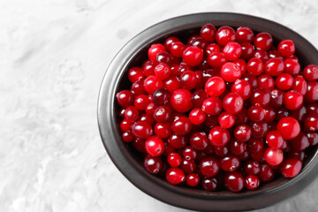 Fresh ripe cranberries in bowl on grey table, top view