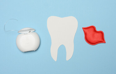 Dental floss and paper tooth on blue background