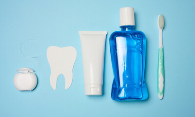 Mouthwash, toothpaste tube, dental floss on a blue background, oral hygiene