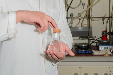 A flask in the hands of a laboratory assistant close-up.