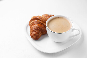 Breakfast time. Fresh croissant and coffee on white background. Space for text