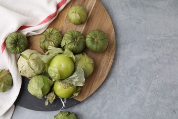 Fresh green tomatillos with husk on gray table, flat lay. Space for text