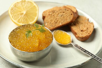 Fresh pike caviar in bowl, lemon and bread on light table, closeup