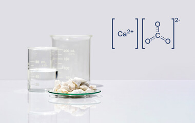 Calcium carbonate chip in chemical watch glass with molecular structure on white laboratory table....