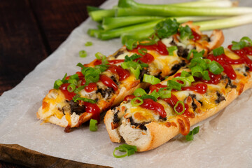 Toasted open-face sandwich made of a sliced baguette  topped with white mushrooms, cheese and ketchup, zapiekanki