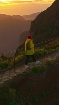 Vertical video. Camera follows woman hiker with backpack. Traveler hiker, enjoys nature and life. Traveling in the mountains, adventure in trip. Woman walking on mountain trail in Madeira