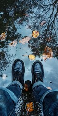 Reflective photo of feet standing next to rain puddles, focusing on the reflection of the sky and surrounding environment in the water