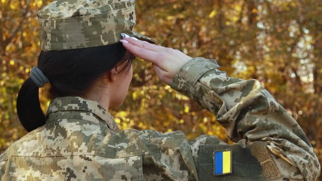 Female servicewoman brave confident soldier salutes respectfully dressed in the camouflage military uniform, patch symbol of independence. Armed Forces of Ukraine. Woman serving in ukrainian army