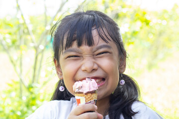 Asian little girl eating ice cream with deliciousness and smile on summer vacation.